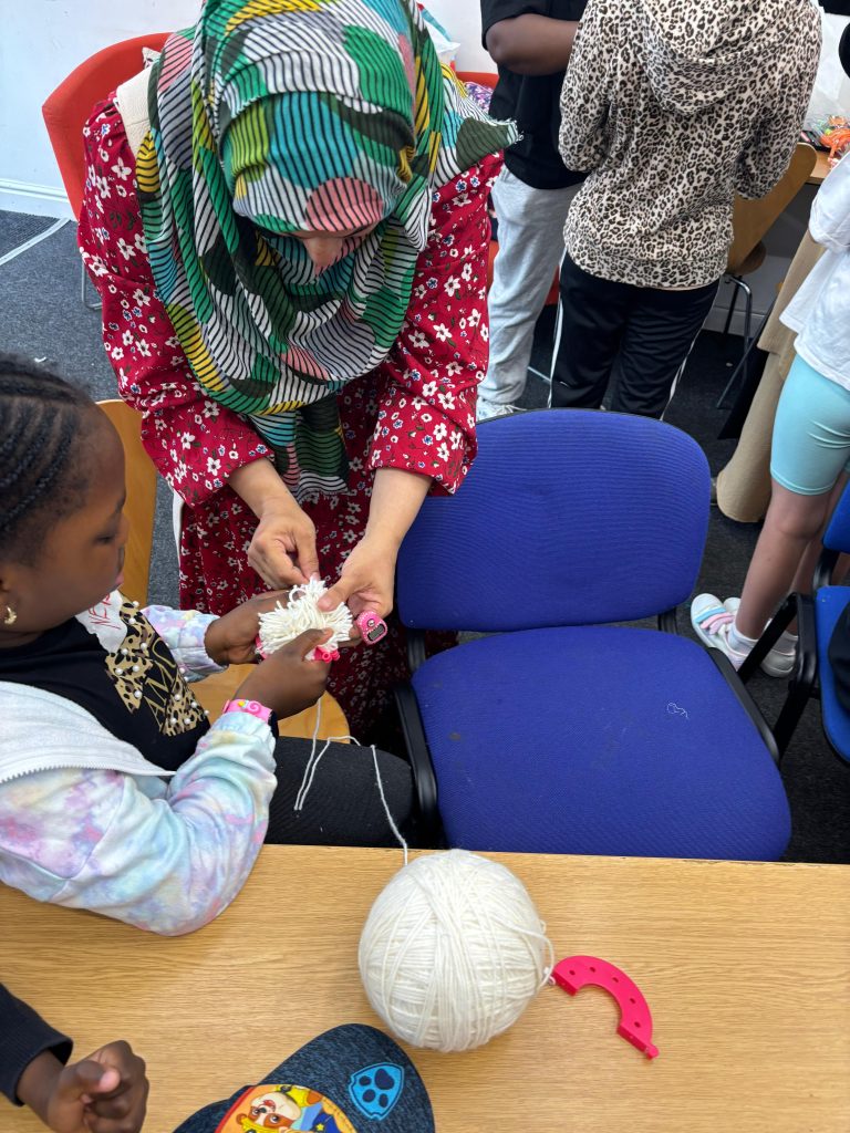 A CAS staff guiding a child through a summer activity instruction 