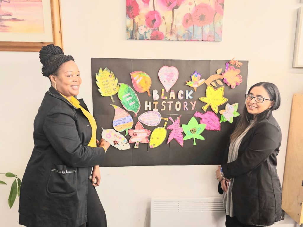 Nicky Iginla, CEO of CAS, and a community member posing with the “Stand Firm in Power and Pride” Black History Month 2025 poster.