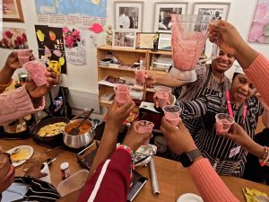 Community members raising drinks in celebration at a community cooking show