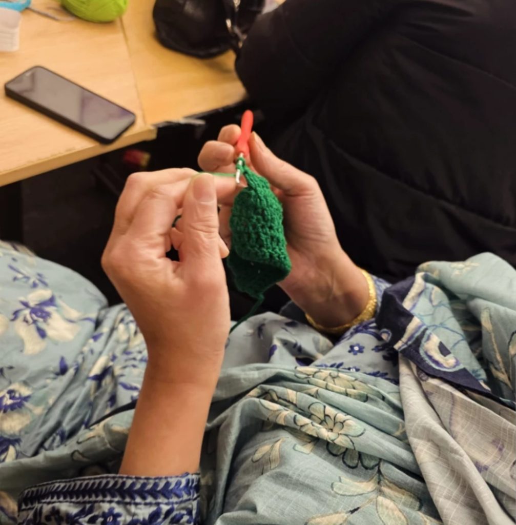 Senior carer crocheting during a community support session