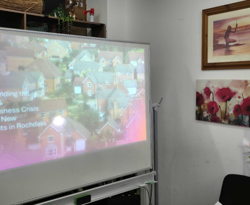 Screen display at the Hub showing the title of the Humanity Project Assembly on housing insecurity in Rochdale.