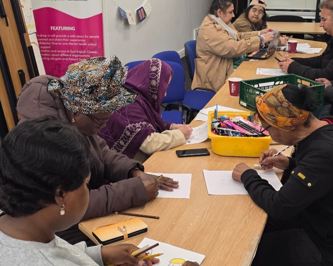 Women participating in a community activity at CAS with a backdrop referencing refugees and asylum seekers