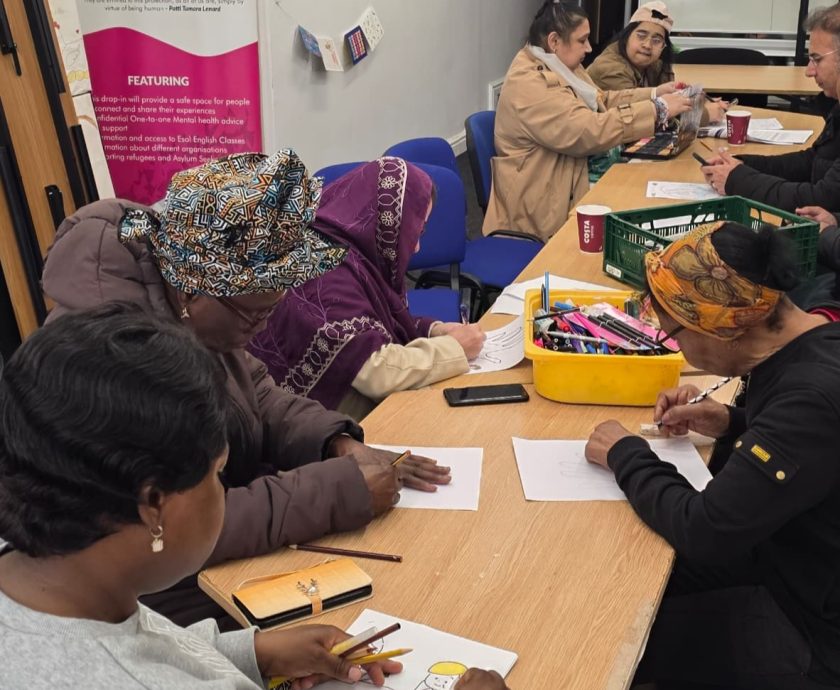 Women participating in a community activity at CAS with a backdrop referencing refugees and asylum seekers